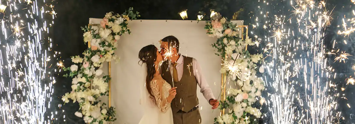 Das Brautpaar in Hochzeitskleidung im Schein der Feuerwerksfunken bei Nacht